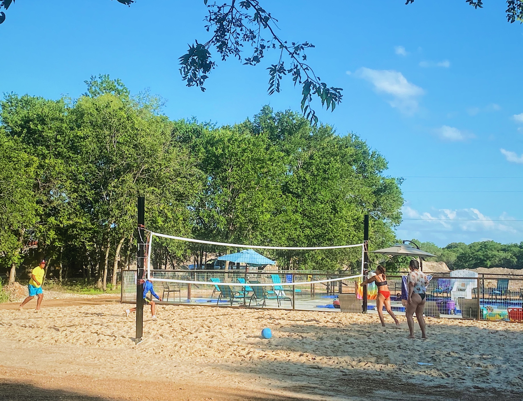 Guests playing volleyball on the sand court