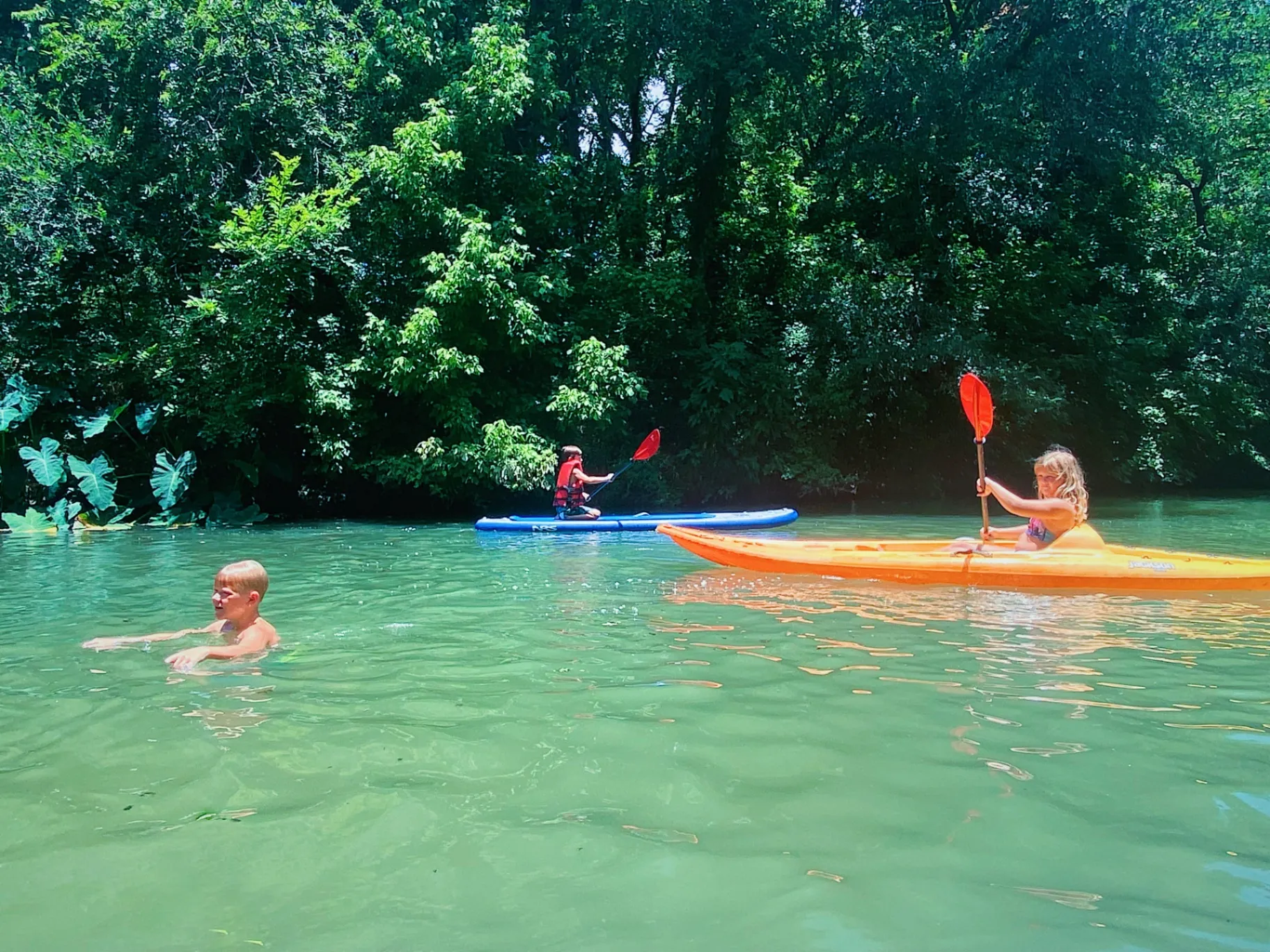Kids swimming and kayaking in the creek